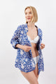Woman wearing a blue floral cover-up over a white bikini on a light gray background