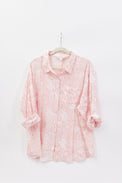 Pink floral blouse on a hanger against a white background