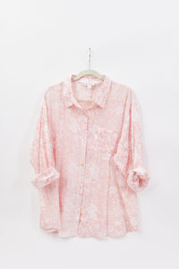 Pink floral blouse on a hanger against a white background
