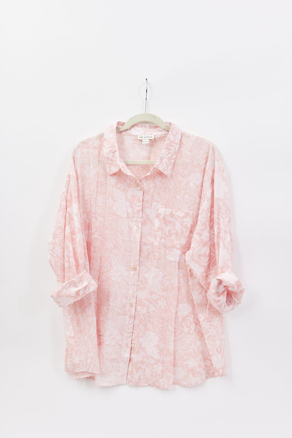 Pink floral blouse on a hanger against a white background