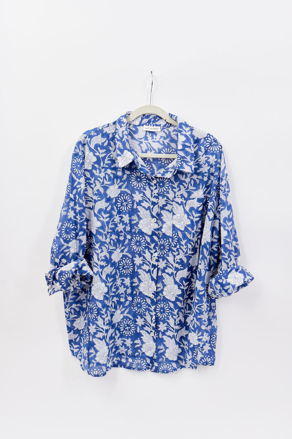 Blue floral blouse on a hanger against a white background