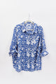 Blue floral blouse on a hanger against a white background