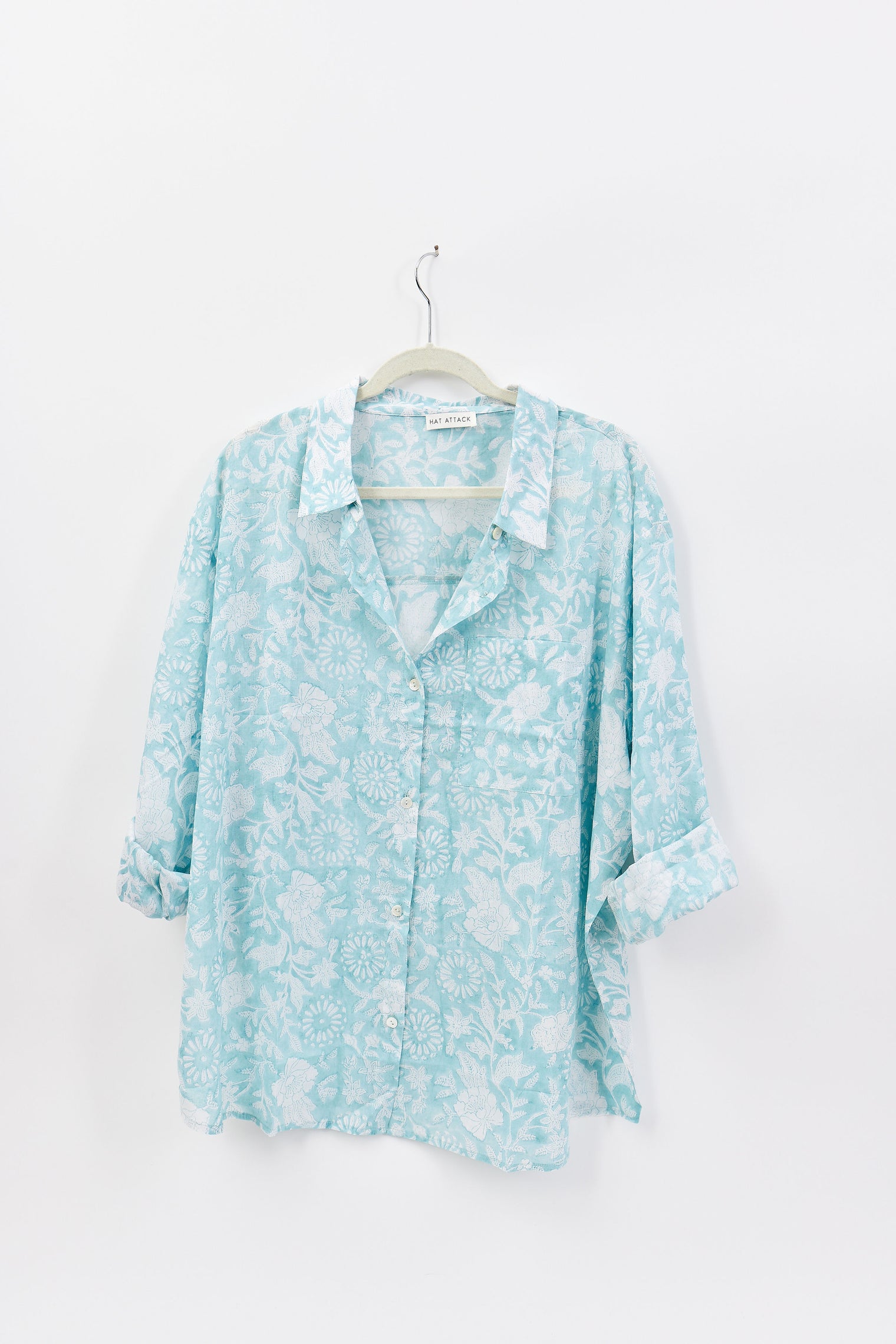 Light blue floral shirt on a hanger against a white background