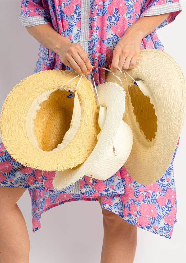Model holding packable travel hat with fringe in bleach, natural and toast