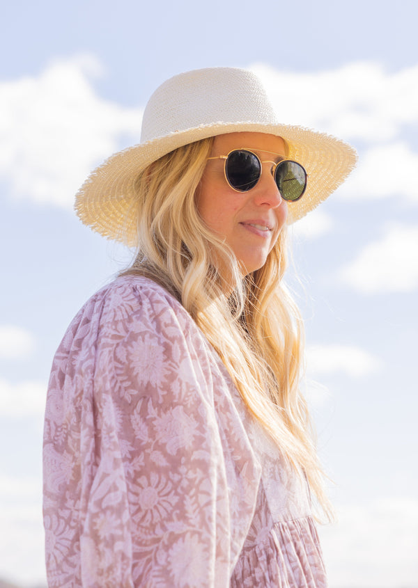 Classic Packable Travel Hat with Fringe in Bleach on beach with sunglasses