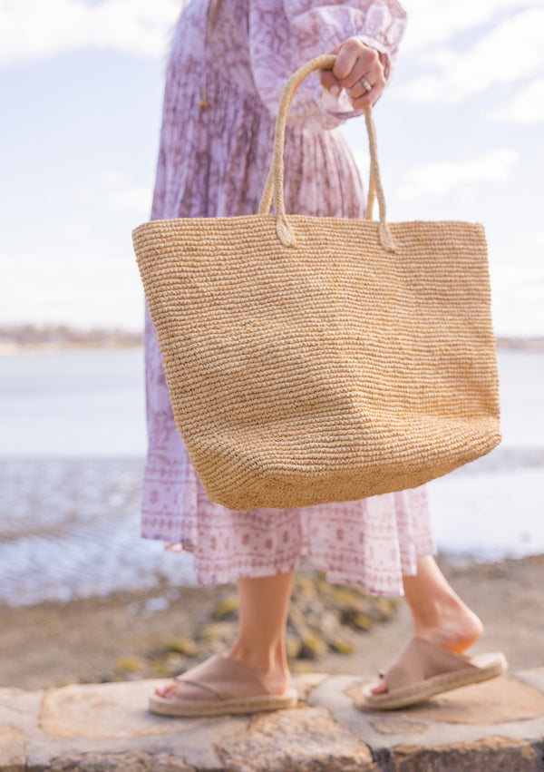 Model holding large straw beach tote