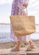 Model holding large straw beach tote