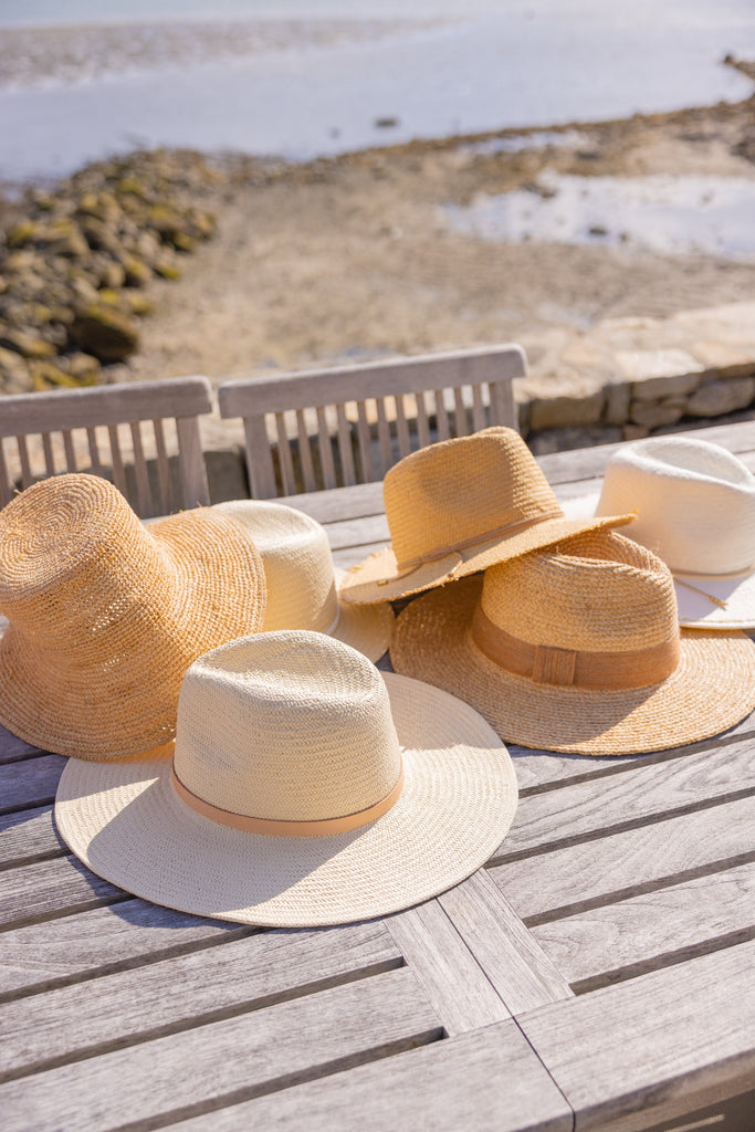 Six straw and raffia hats on a table