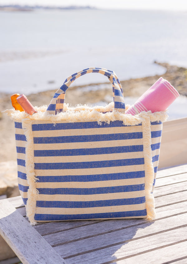 Canvas cooler tote in denim stripe on picnic table by the water