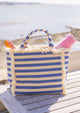 Canvas cooler tote in denim stripe on picnic table by the water