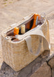 Straw cooler tote with wine bottles inside at the beach