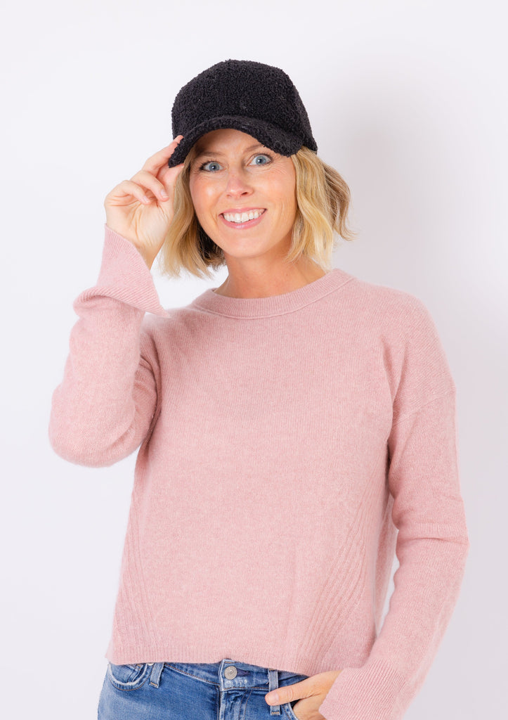 Sherpa Cap in black on model in pink sweater holding brim and smiling