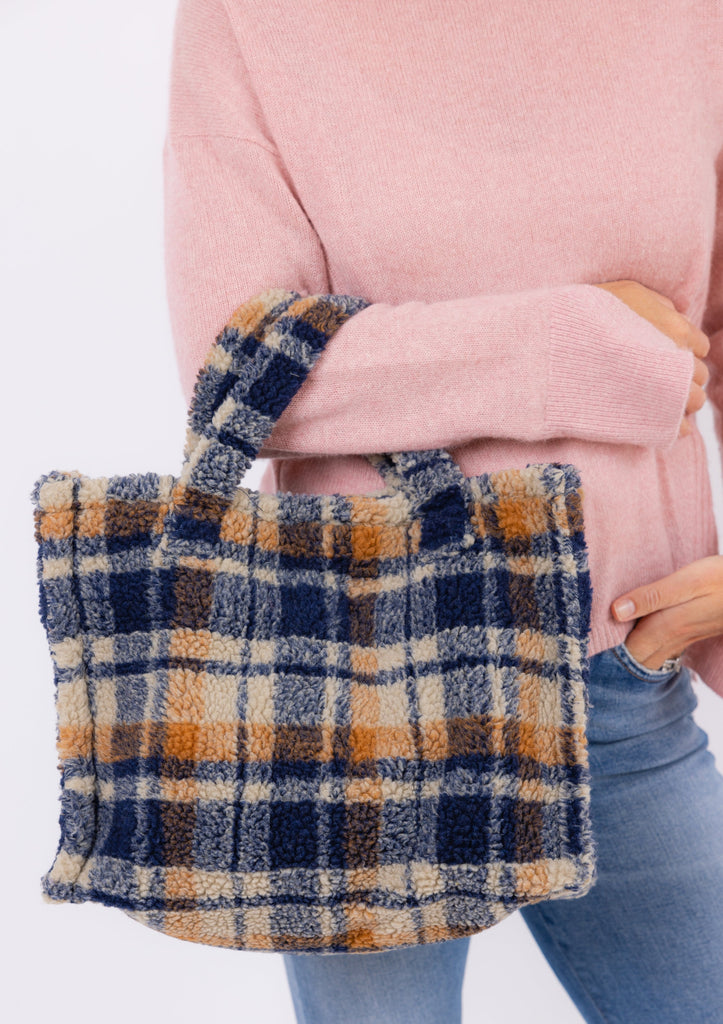 Model holding small teddy tote with hand in her pocket