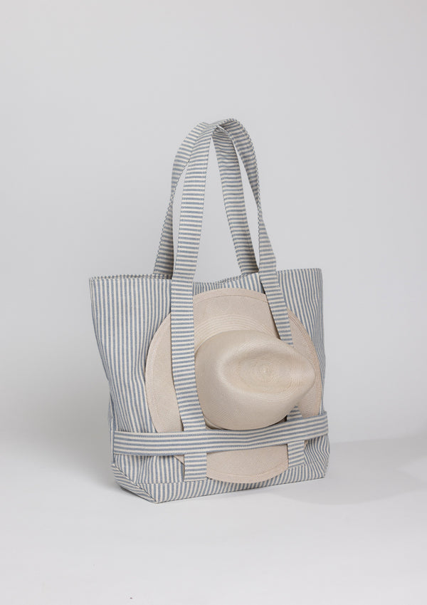 3/4 angle of a Navy stripe canvas bag holding a hat with attached straps