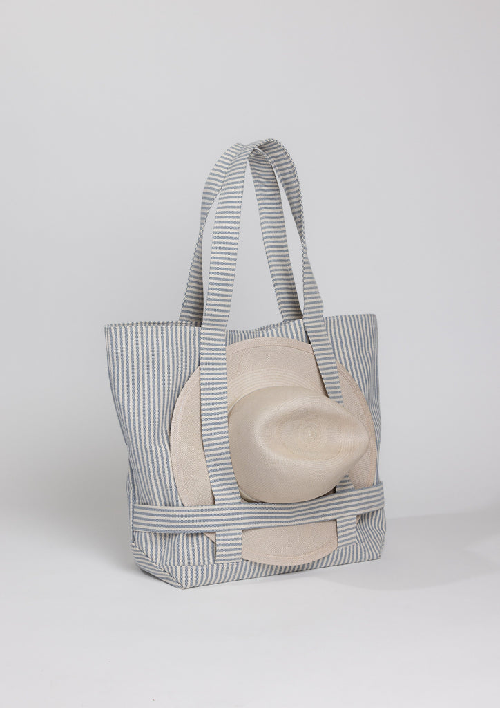 3/4 angle of a Navy stripe canvas bag holding a hat with attached straps