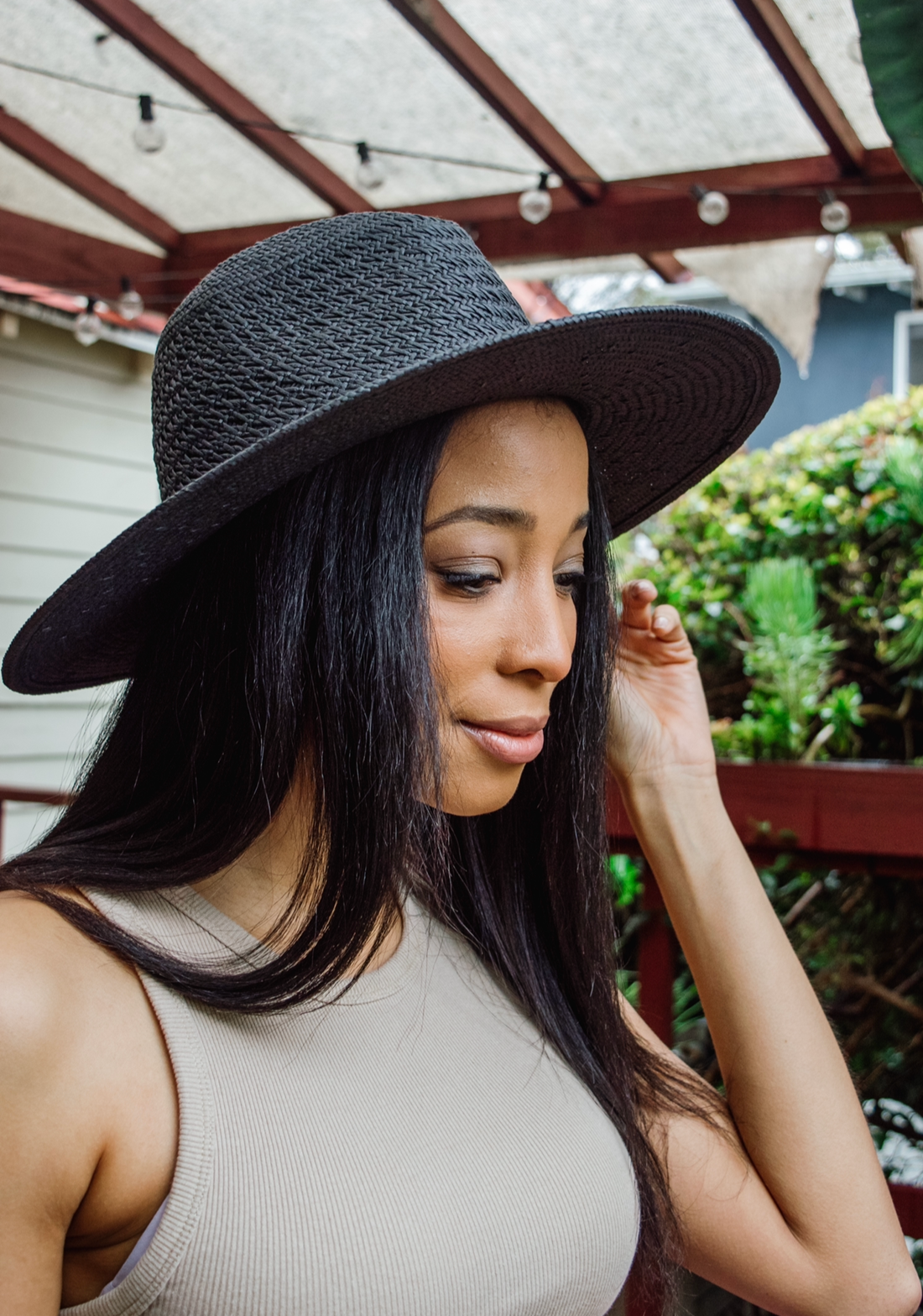 Model holding brim of black sun hat