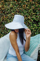 Packable white canvas hat on model holding brim