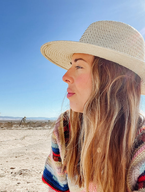Model wearing a brimmed sun hat in the desert