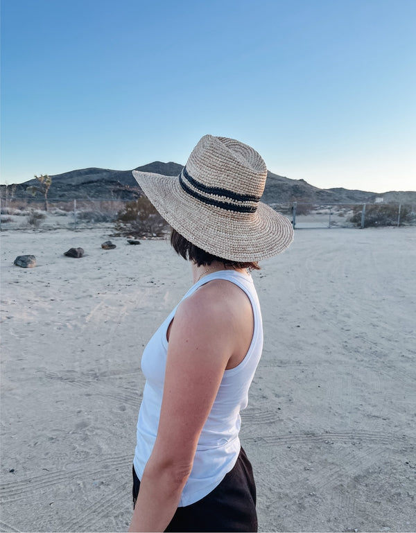 Model wearing sun hat with double black stripe detail in the desert