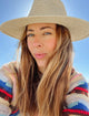 Model wearing colorful sweater and tan straw perforated sun hat