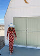Model walking in front of a shed wearing a white perforated sun hat