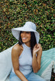 White packable sun hat on model with greenery