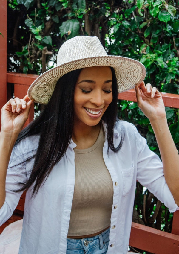 Model wearing a tan and white sun hat and looking down 