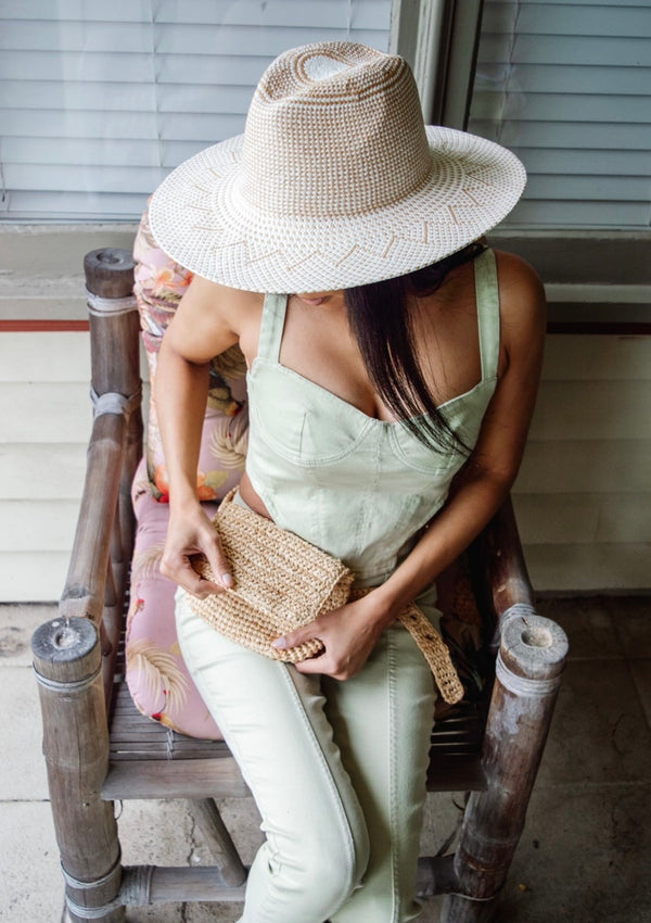 Model wearing straw belt bag and tan and white sun hat